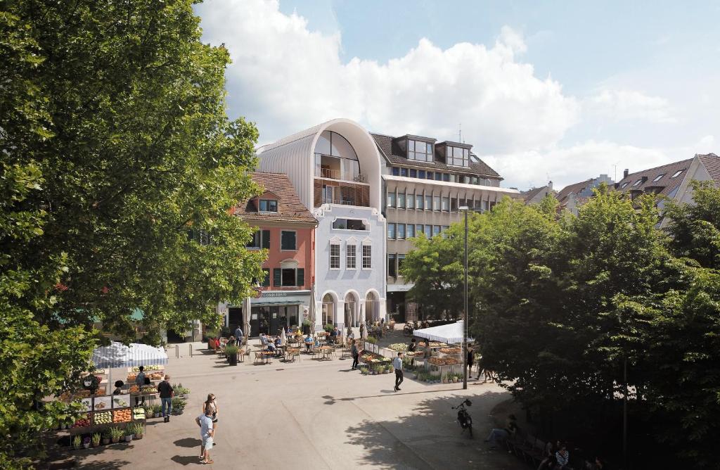 a group of people sitting in a plaza in front of a building at kleiner Löwe – Stadthotel Bregenz in Bregenz