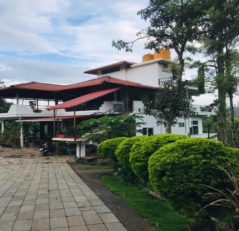 a large white building with trees in front of it at Sana Estate Stay in Madikeri