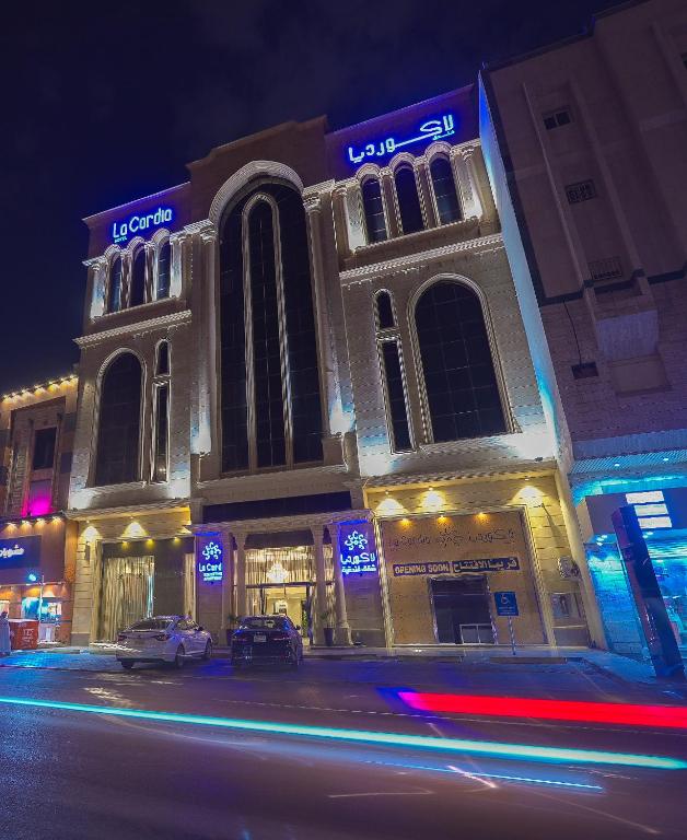 a lit up building on a city street at night at Ajyal Al Madinah La Cordia Hotel Apartment in Medina
