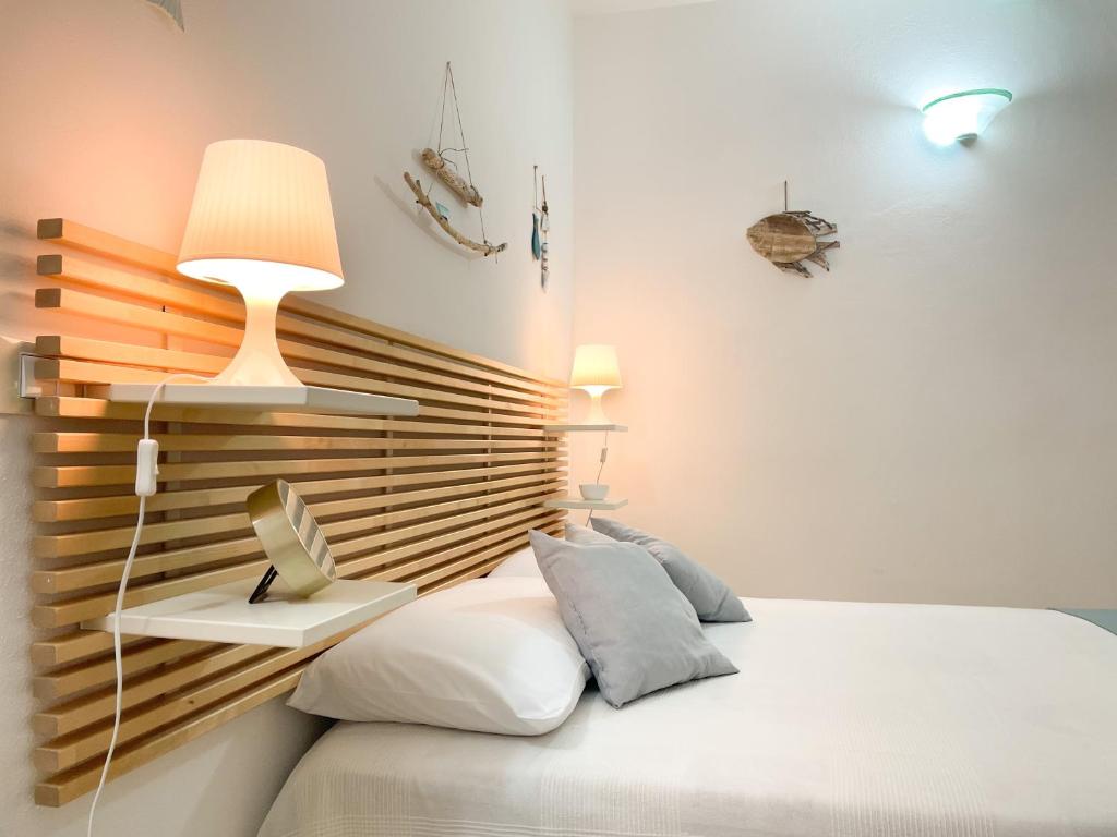 1 dormitorio con cama blanca y cabecero de madera en Piccolo Loft Sabbia e Sassi - Incantevole Loft sulla Costa dei Trabocchi, en San Vito Chietino