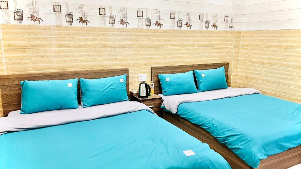 twee bedden in een kamer met blauwe kussens bij Uyên House hotel in Da Lat