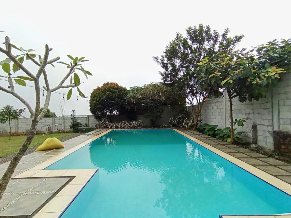 a swimming pool with blue water in a yard at Villa Cisarua Kerucut in Brujul