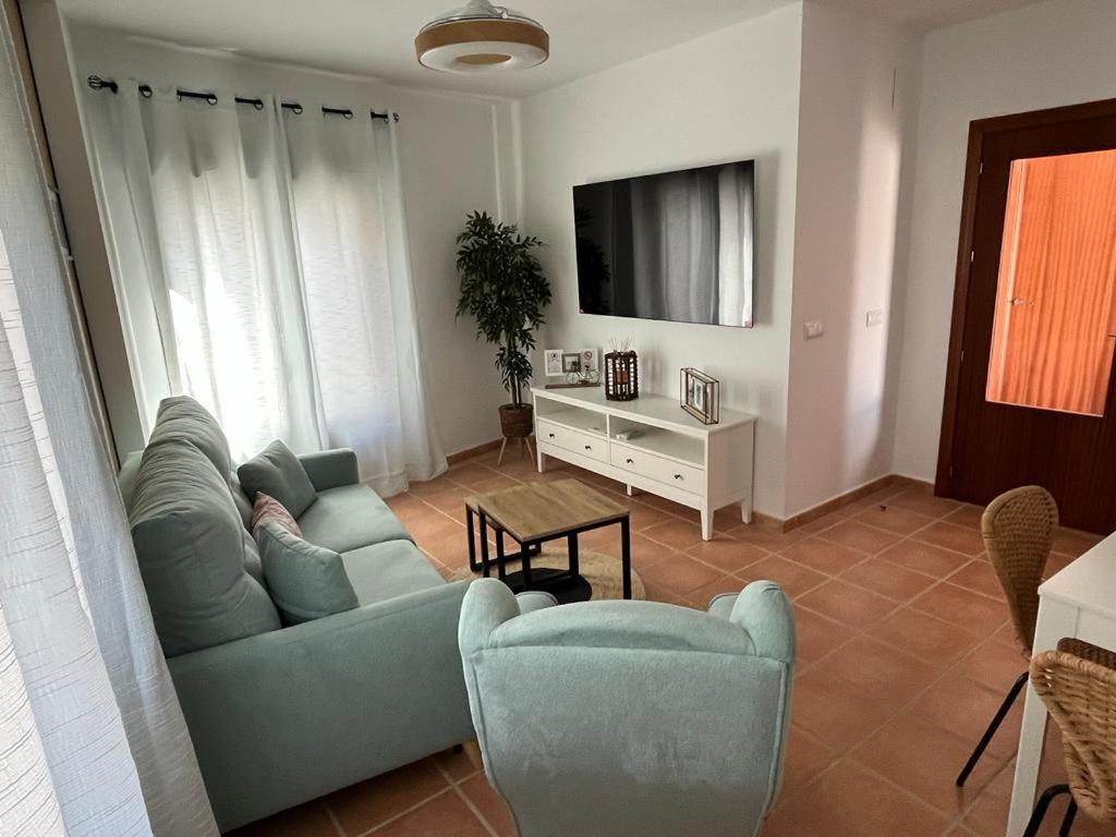 a living room with a couch and chairs and a tv at El Balcón de Fuenteheridos in Fuenteheridos