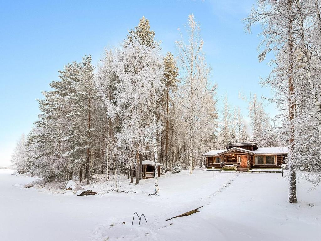 a cabin in the woods with snow covered trees at Holiday Home Papanmökki by Interhome in Huuhanaho