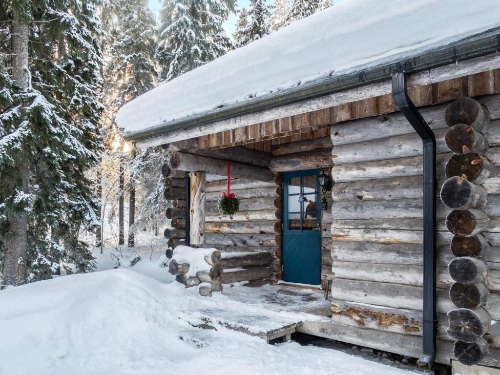 domek z bali z niebieskimi drzwiami w śniegu w obiekcie Holiday Home Vuokatinportti a 9 by Interhome w mieście Lahdenperä