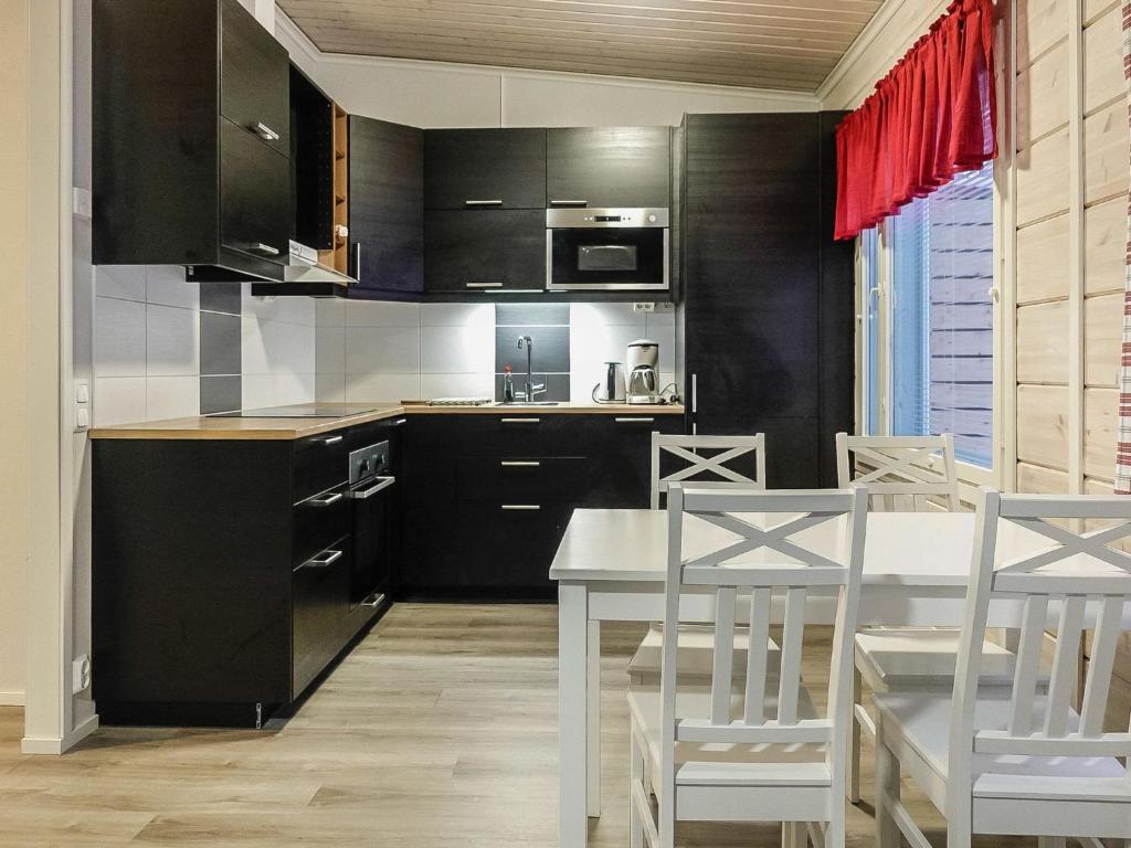 a kitchen with black cabinets and a table and chairs at Holiday Home Levin revontulitaivas a by Interhome in Köngäs