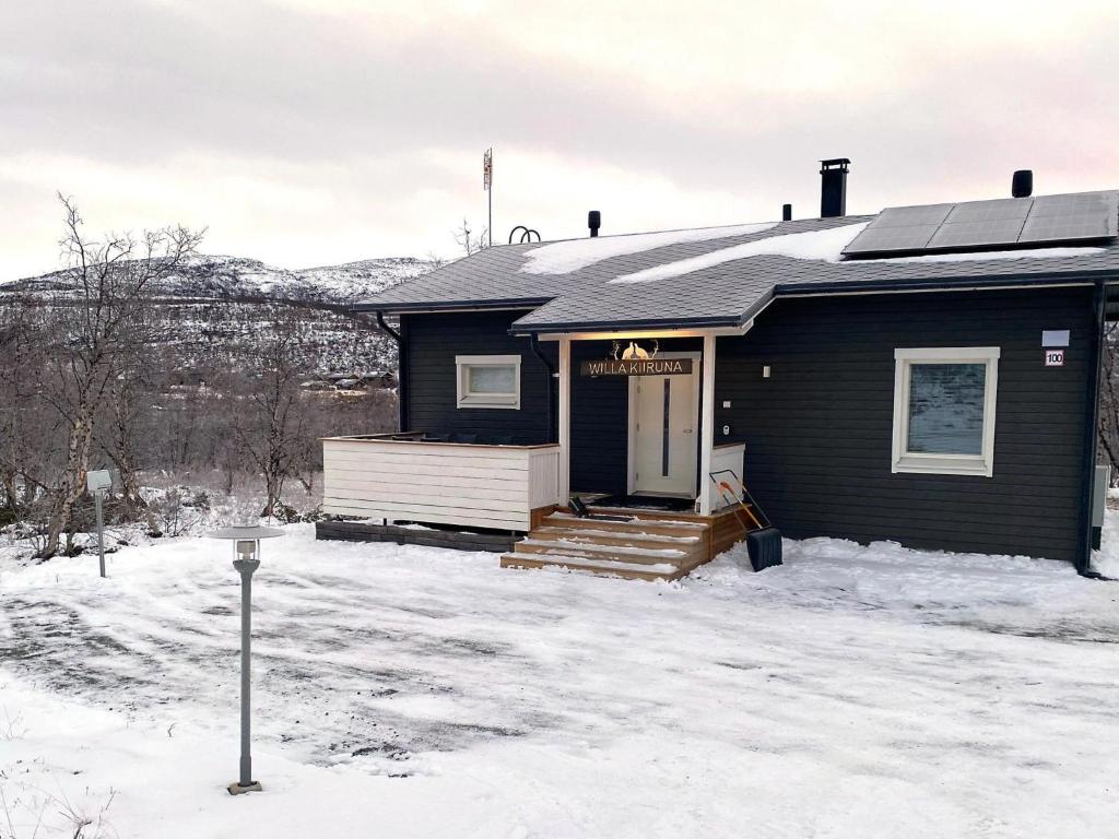 a black house with a porch in the snow at Holiday Home Willa kiiruna by Interhome in Kilpisjärvi