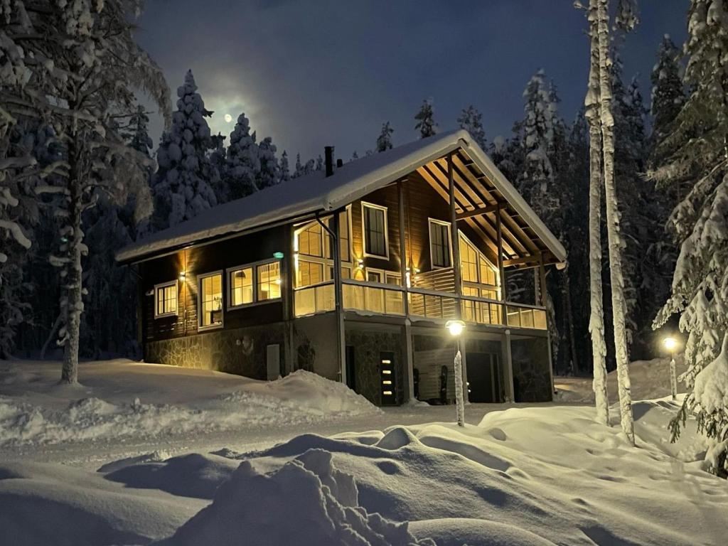 a log cabin in the snow at night at Holiday Home Herrasmäki by Interhome in Sirkka
