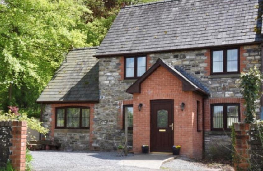 a brick house with a door in a driveway at Tregib Mill Cottage in Ffair-fâch