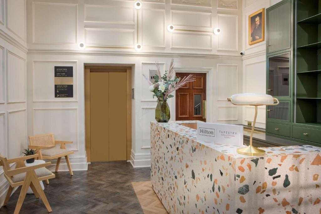 a room with a counter with a vase of flowers on it at The Samuel Ryder Hotel St Albans, Tapestry Collection Hilton in St. Albans