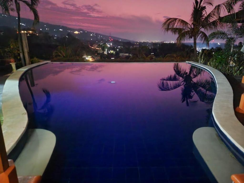 a blue swimming pool with a view of a city at The Dharma Araminth Villa - Lovina Mountain and Sea View in Lovina