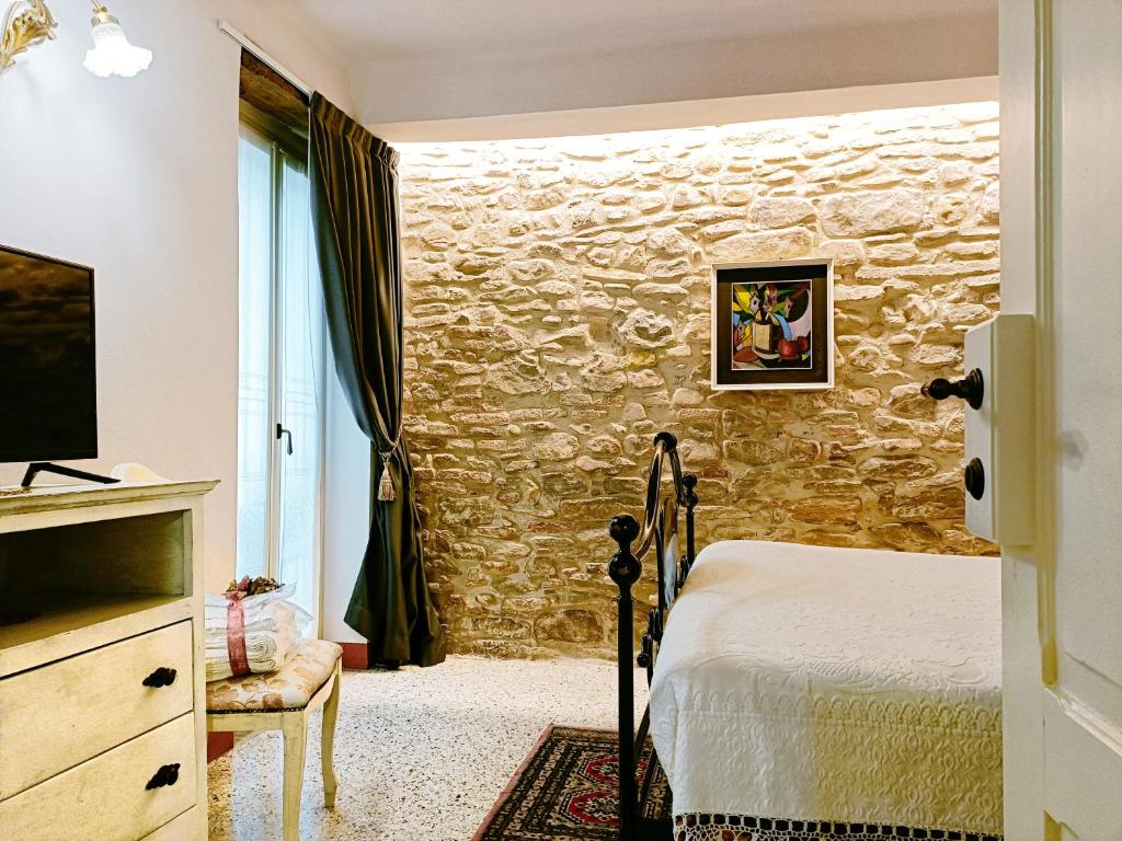 een slaapkamer met een bed en een stenen muur bij Casa rustica tra mare e collina in Morciano di Romagna