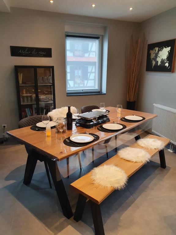 a wooden table with plates and glasses on top of it at Appartement, proche Europa-Park Colmar Strasbourg in Sundhouse