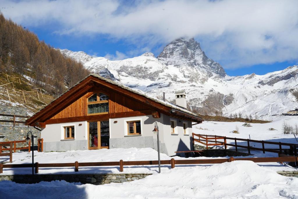 a house in the snow with a mountain in the background at FAIRWAY LODGE in Breuil-Cervinia