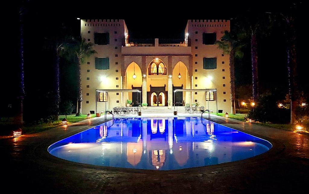 - une grande piscine en face d'un bâtiment la nuit dans l'établissement Kasbah ATFEL, à Ourika