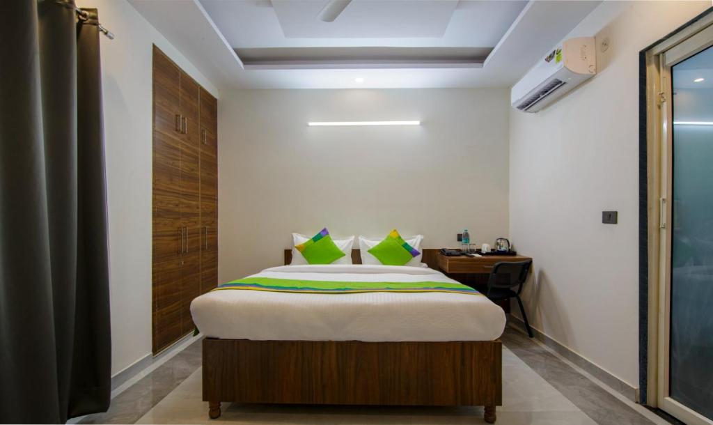 Habitación pequeña con cama y escritorio. en Hotel Grand Vista en Noida