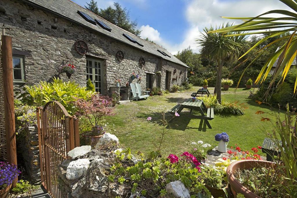 ein Garten vor einem Steinhaus mit Blumen in der Unterkunft Dolly's Barn at Higher Mullacott in Ilfracombe