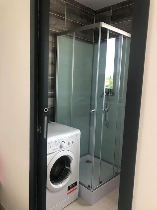 a washing machine and a glass shower in a bathroom at Studio Rousson in Rousson