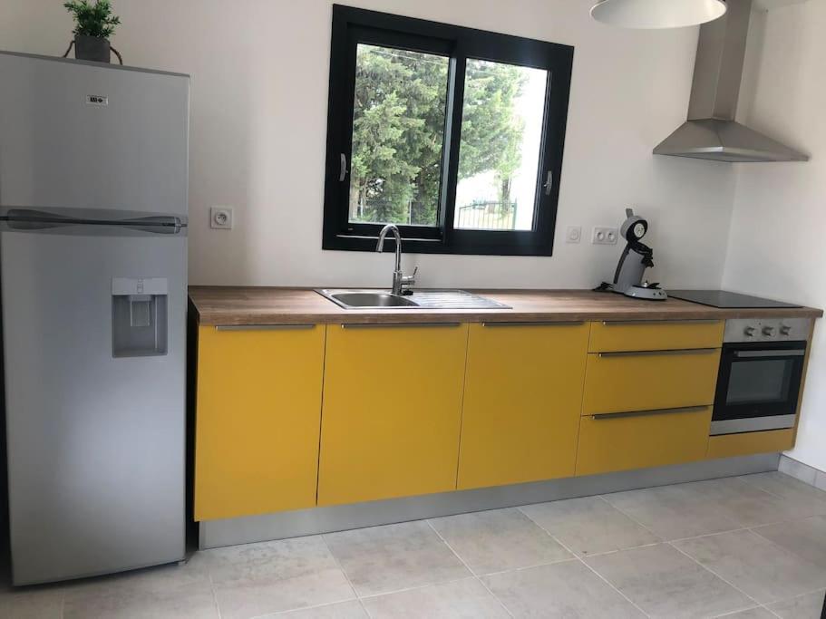 a kitchen with yellow cabinets and a sink and a window at Studio Rousson in Rousson