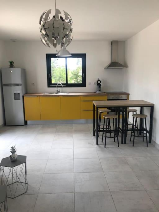 a kitchen with yellow cabinets and a table and chairs at Studio Rousson in Rousson