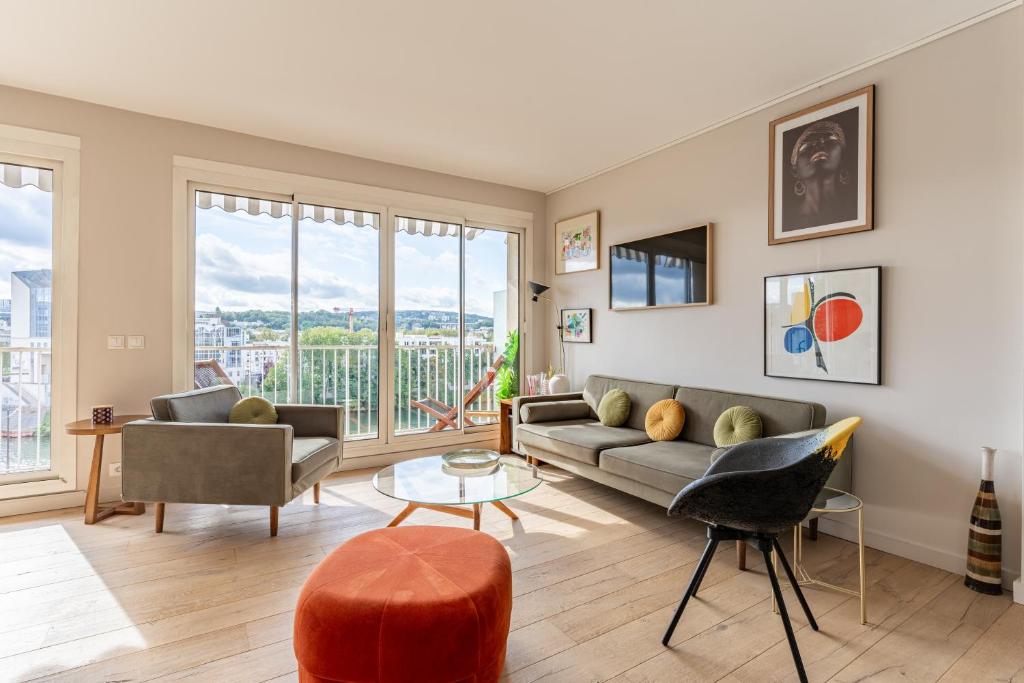 a living room with a couch and a table at Quai de Seine - Vue sur la Seine in Boulogne-Billancourt