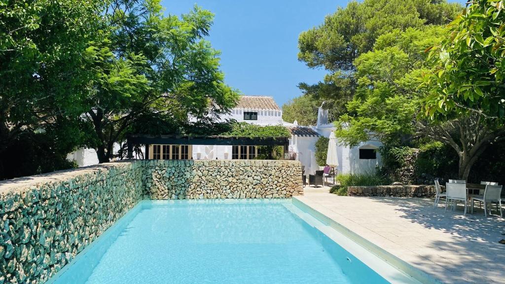 a swimming pool in front of a house with a stone wall at Holiday Home Casa MADORIA in Sant Climent