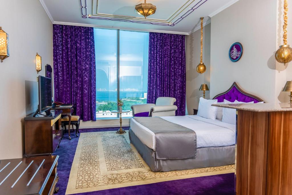 a hotel room with a bed and a large window at Saraya Corniche Hotel in Doha