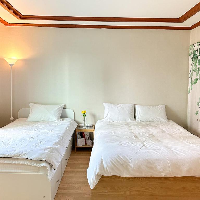 two beds sitting next to each other in a bedroom at Hue Stay in Ansan