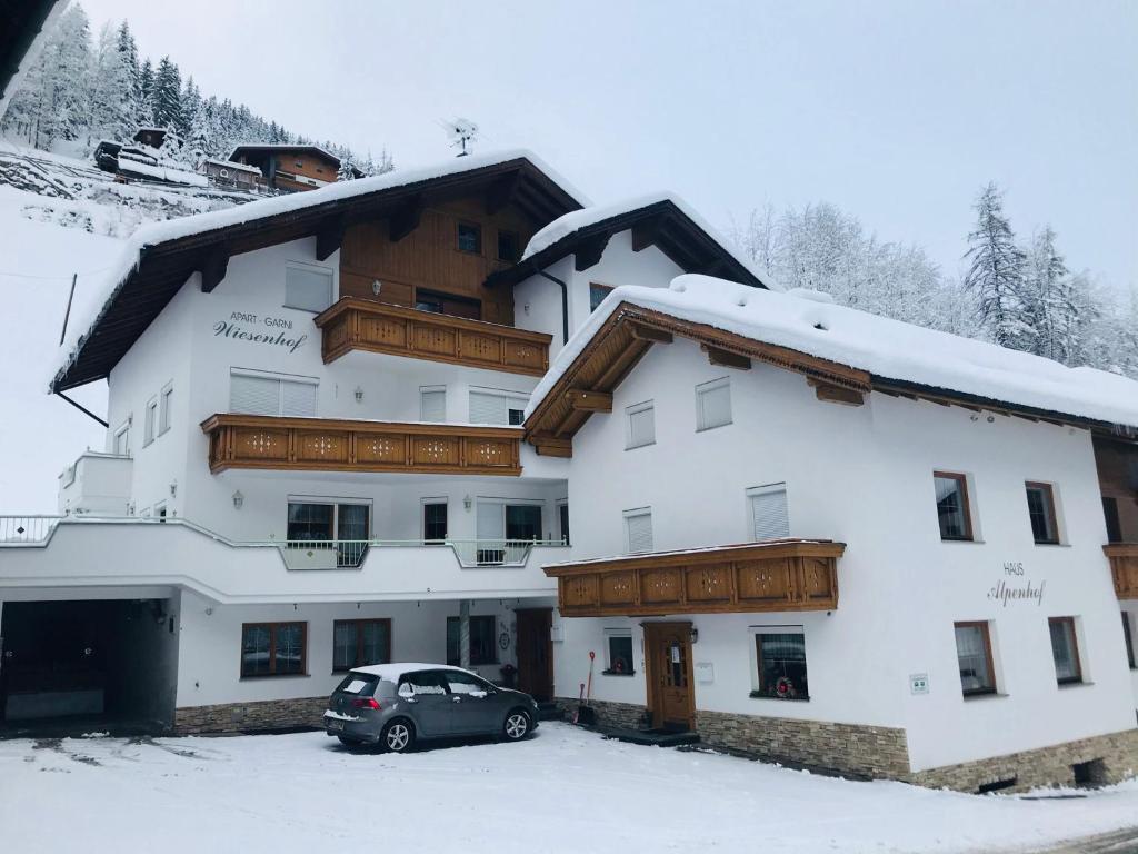 um edifício com um carro estacionado na neve em Apart Garni Wiesenhof em Kappl