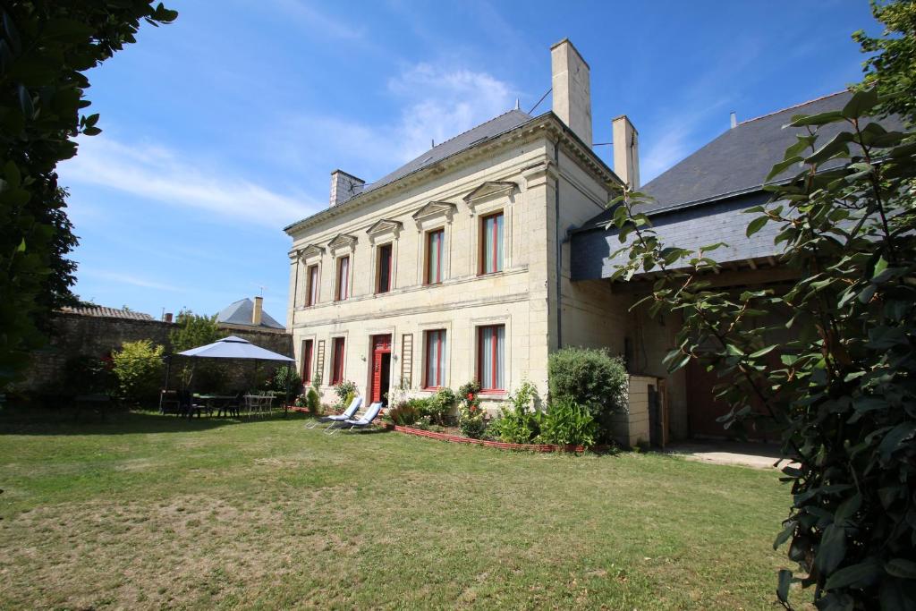 una grande casa bianca con porte rosse e un cortile di Domaine Des Roses a Vaudelnay