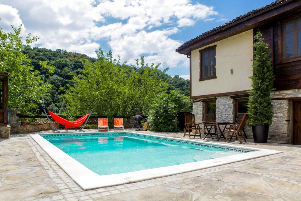 a swimming pool with chairs and a house at Veliko Tarnovo Villa Lora in Veliko Tŭrnovo