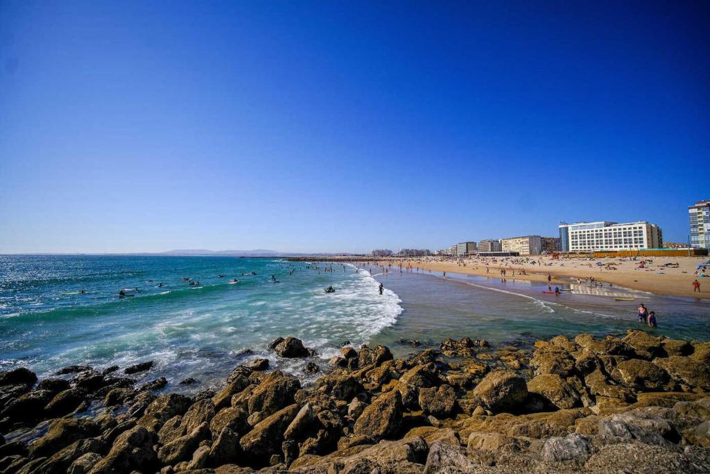 a beach with people in the water and rocks at Sunny Beachfront Apt in Costa da Caparica in Almada