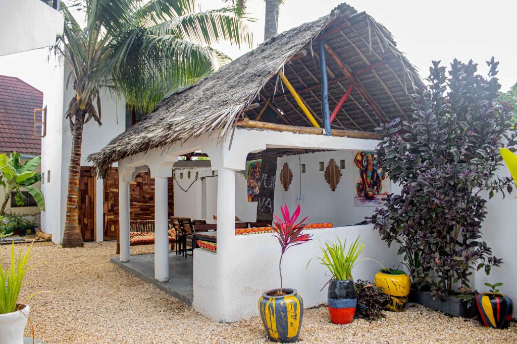 Biały dom z dachem krytym strzechą i roślinami w obiekcie Light of Zanzibar Hotel w mieście Nungwi