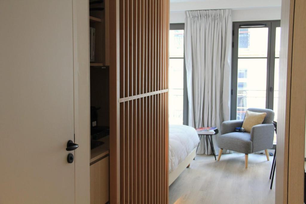 a bedroom with a bed and a chair and a window at FINESTATE Coliving Champs-Elysées in Paris