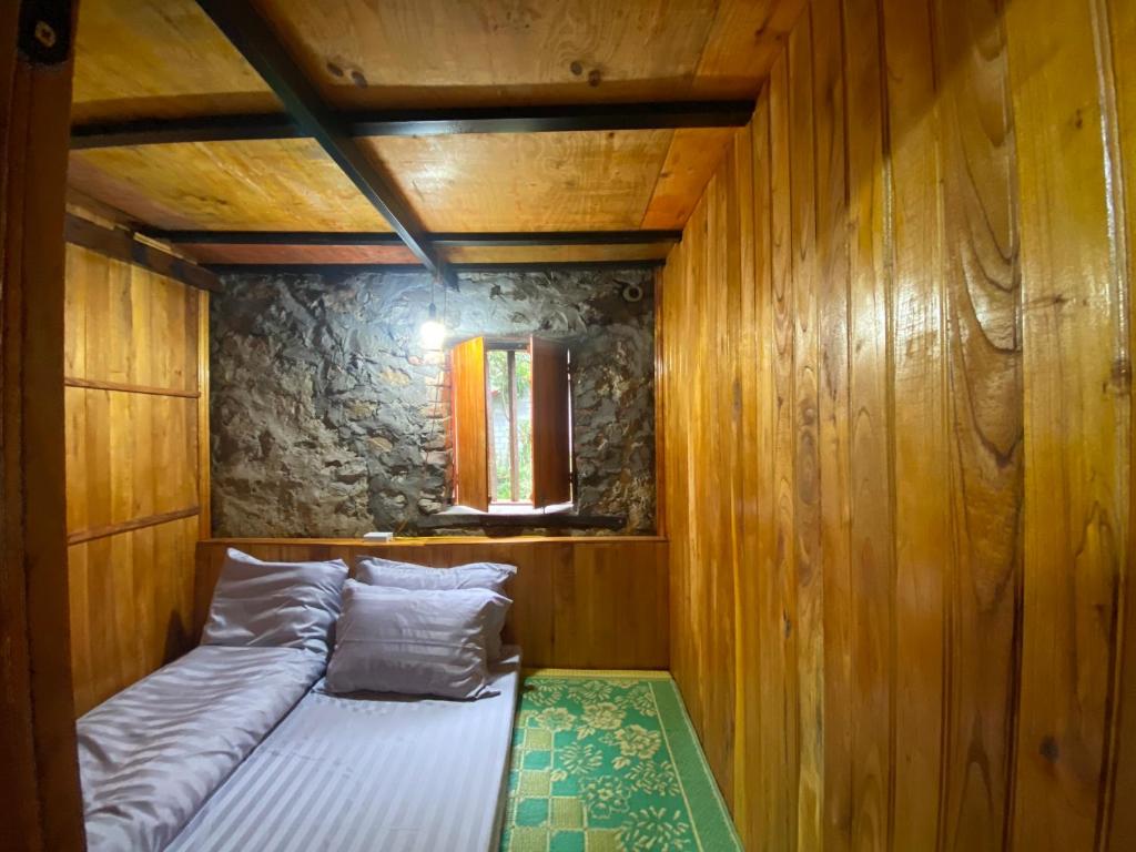 a small bed in a room with wooden walls at Triệu Chương Homestay in Cao Bằng