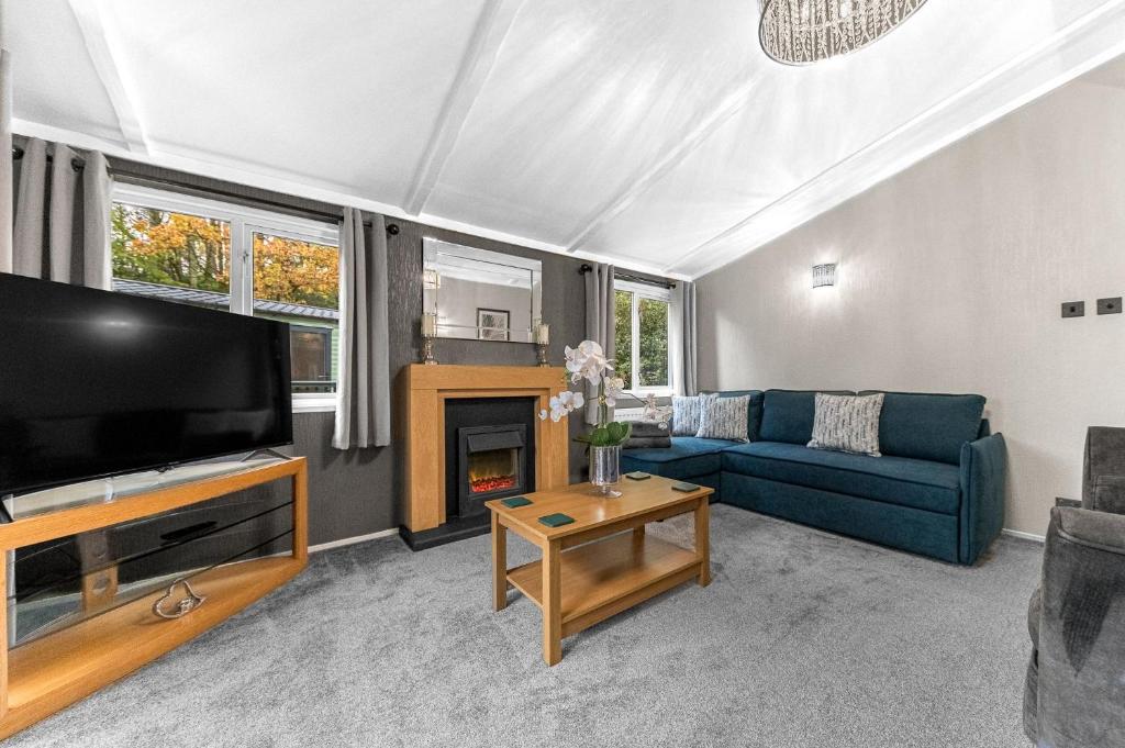 a living room with a blue couch and a tv at Firgarth Lodge in Windermere