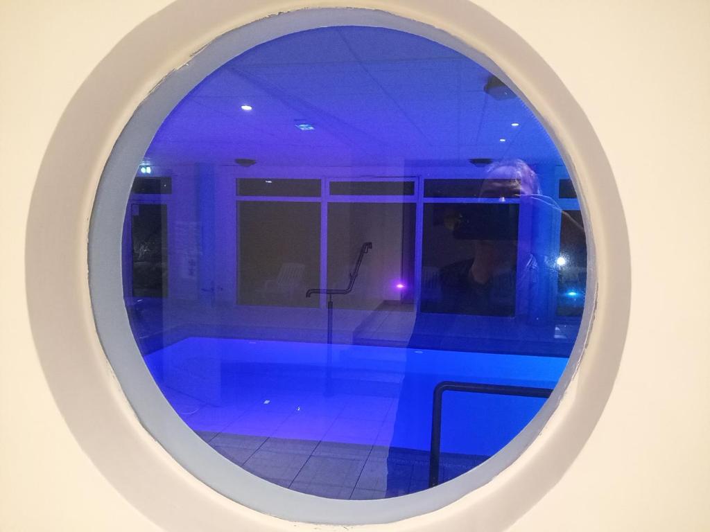 una ventana redonda en una habitación con piscina en Le Repaire du Golfeur de la Largue - Mooslargue en Mooslargue