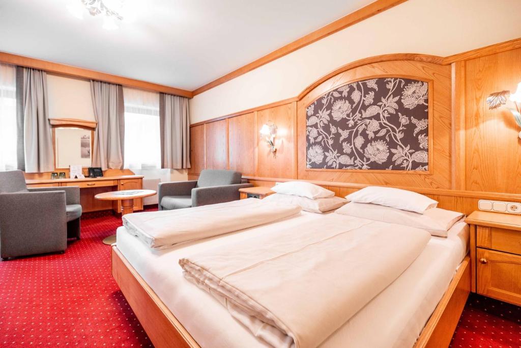a hotel room with a large bed and chairs at Hotel Das Walchsee in Walchsee