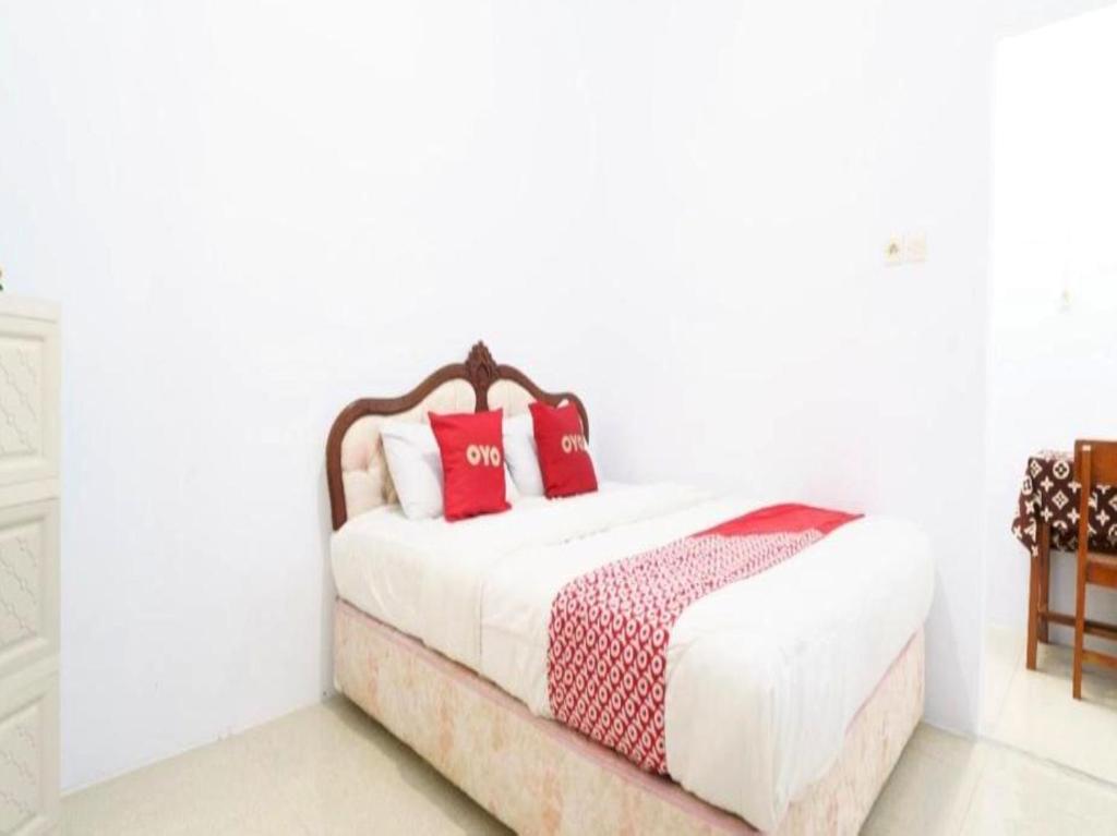 una camera bianca con letto con cuscini rossi di OYO 93249 Wisma Jasmine Syariah a Kuningan
