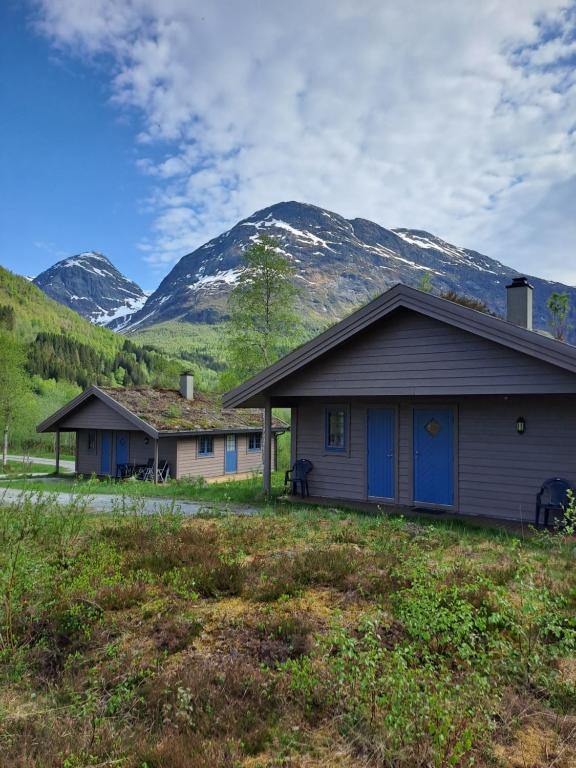 a house with blue doors and mountains in the background at Stardalen Hyttegrend in Klakegg