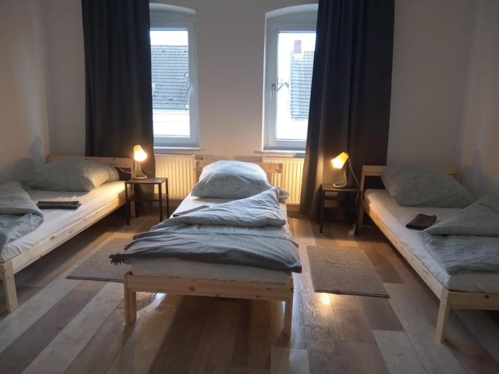 dwa łóżka siedzące w pokoju z dwoma oknami w obiekcie Ideale Unterkunft für Geschäftsreisende, Studenten, Monteure in Essen w Essen