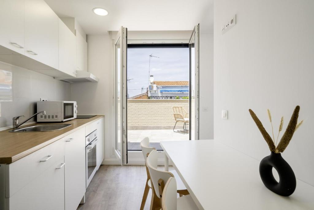 een keuken met witte kasten en een aanrecht met een tafel bij apartamentos en vallecas in Madrid
