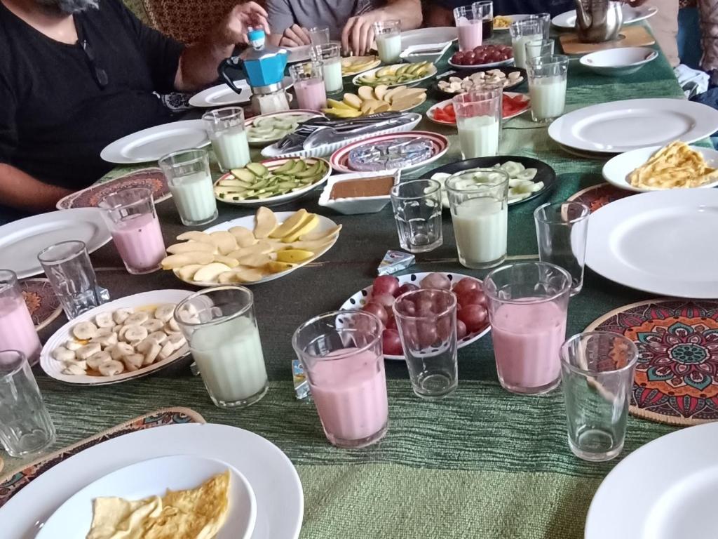 uma mesa com pratos de comida e copos de leite em Sunrise Hostel Taghazout em Taghazout