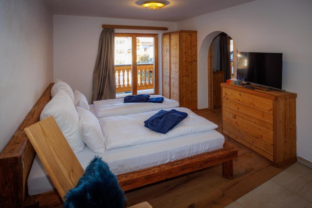um quarto com uma cama com lençóis brancos e uma televisão em Alpenloft 2 em Mittenwald