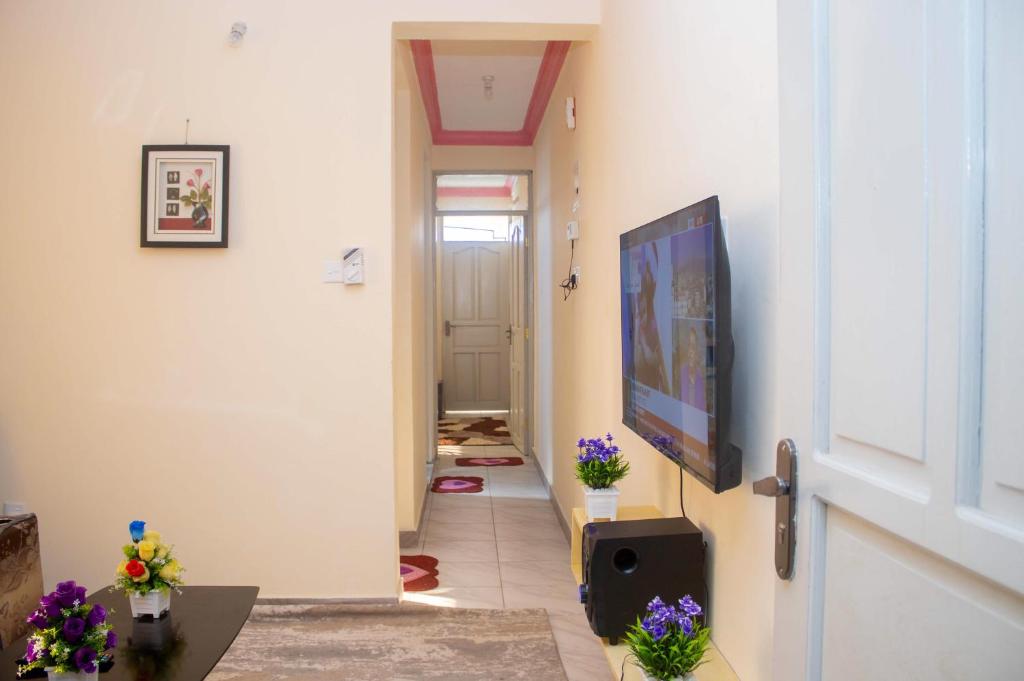 a hallway with a television and flowers on the floor at At's Apartment in Mombasa