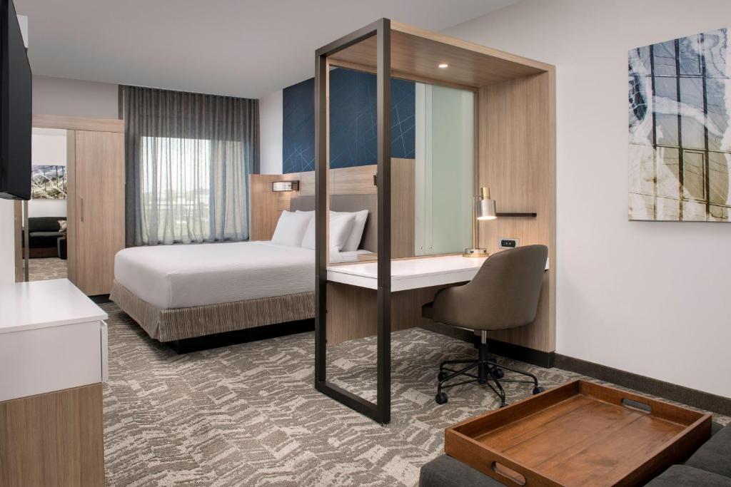 a hotel room with a bed and a desk with a mirror at SpringHill Suites by Marriott Cincinnati Mason in Mason