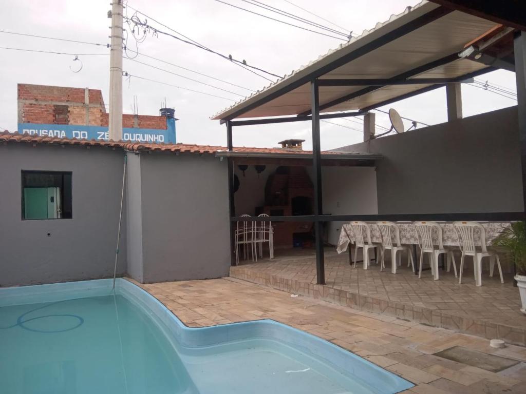 a house with a swimming pool and a patio with chairs at CASA PARA VISITANTES E ROMARIAS DA NOSSA SRA. DE APARECIDA in Aparecida