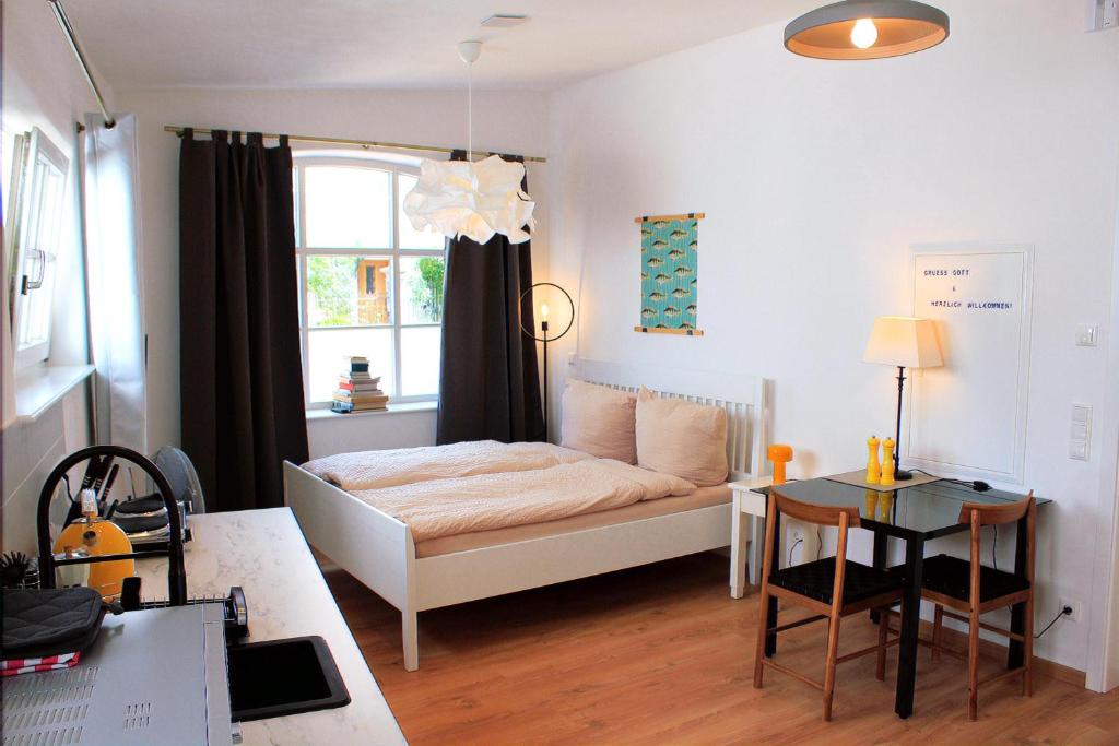 Dormitorio pequeño con cama y mesa en Barrierefreie Ferienwohnung ideal für Paare, en Dießen am Ammersee