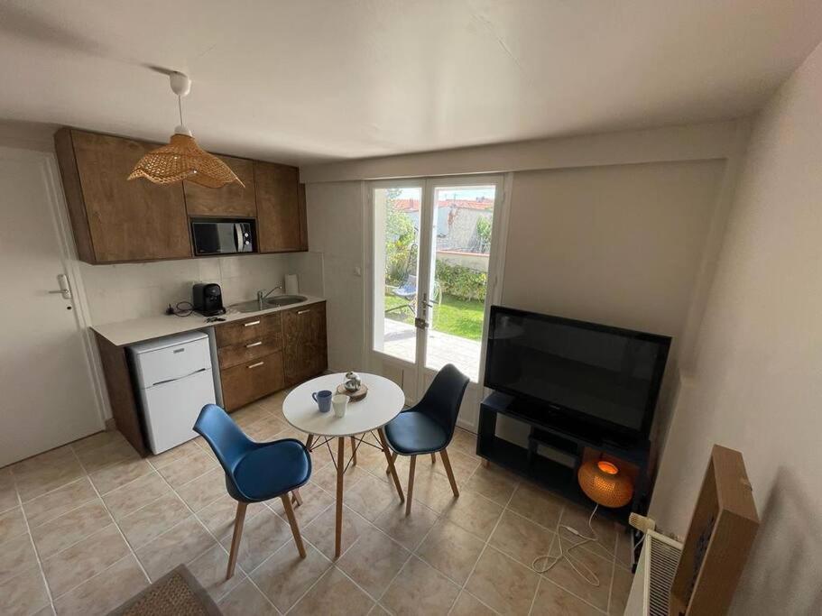 une cuisine avec une table et des chaises et une télévision dans l'établissement La Rochelle Rdc de maison proche Ile de Ré, à La Rochelle
