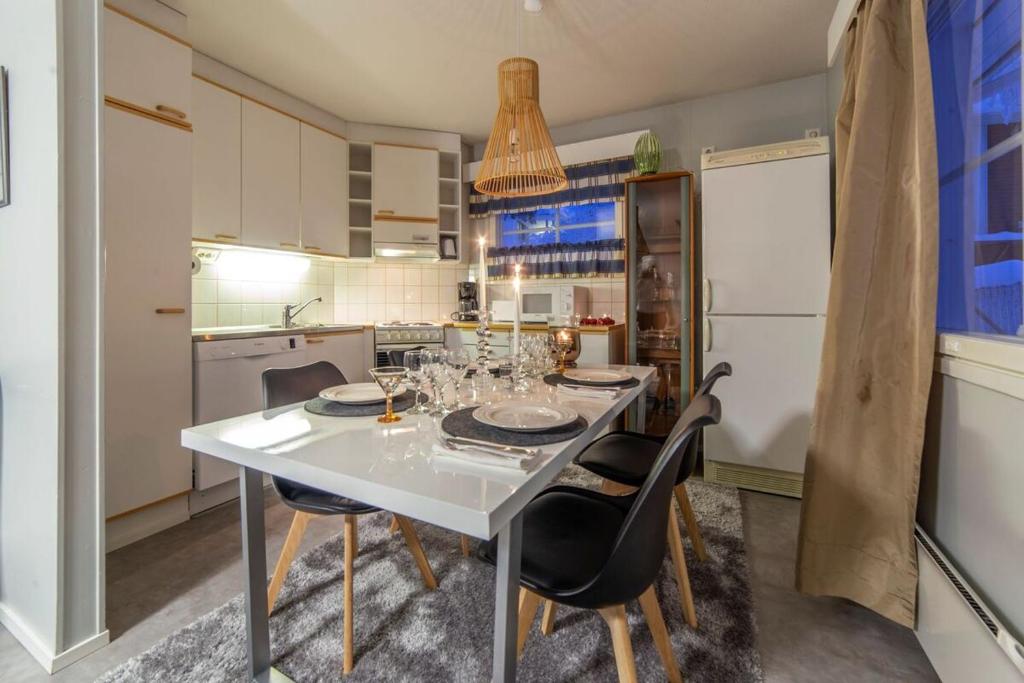 a kitchen with a white table and chairs in a room at Kuukkeli Apartments in Saariselka